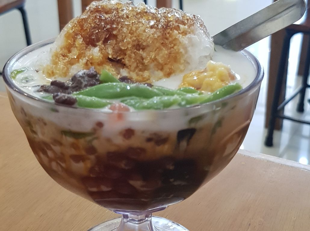 Segelas Es Cobra dengan cincau hitam, nata de coco, kelapa muda, dan sirup cocopandan, menyegarkan hari Anda
